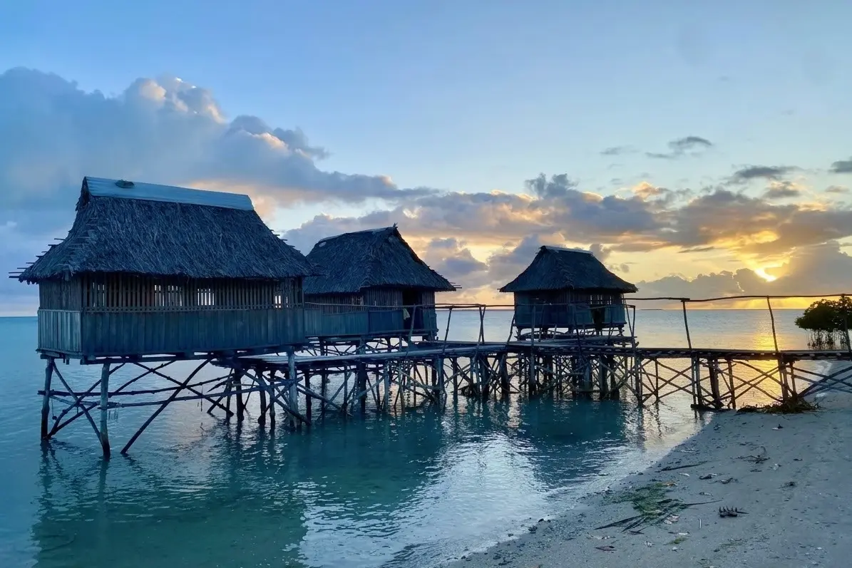 Traditional stilt structures on the water's edge in Kiribati, where communities face the frontline realities of sea-level rise and coastal change