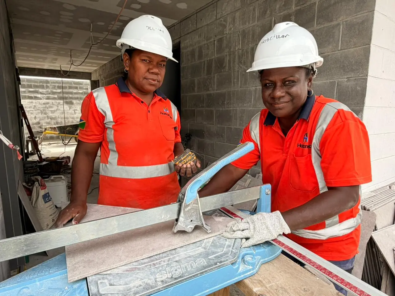 Two trainees cutting tiles on the Seghe Market construction site. The Australian High Commission says Australia's infrastructure projects are helping young women and men build skills and a career in construction.