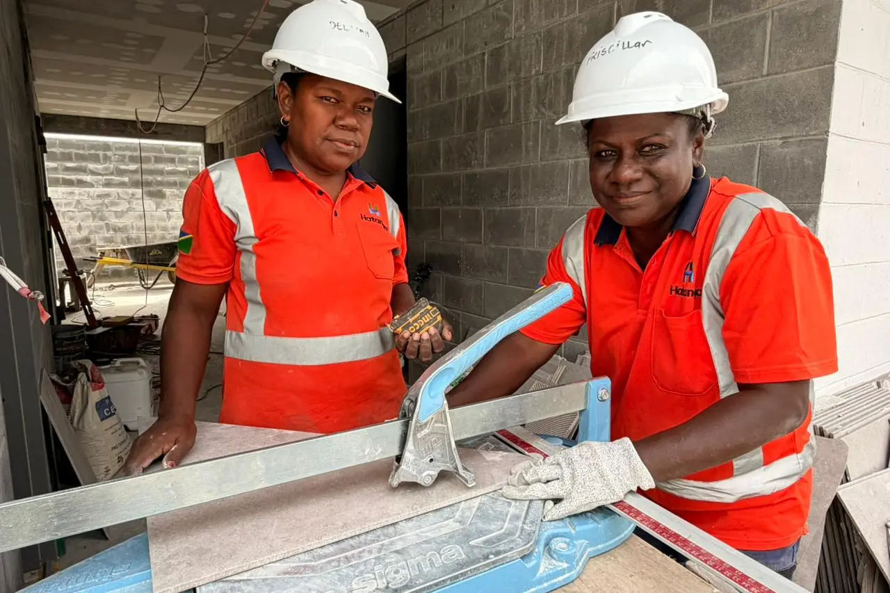 Two trainees cutting tiles on the Seghe Market construction site. The Australian High Commission says Australia's infrastructure projects are helping young women and men build skills and a career in construction.