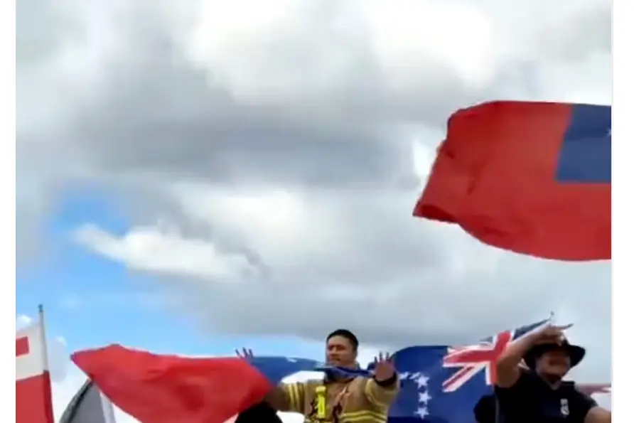 Firefighters on a fire truck draped in Pacific flags during Rugby League World Cup celebrations in Auckland.