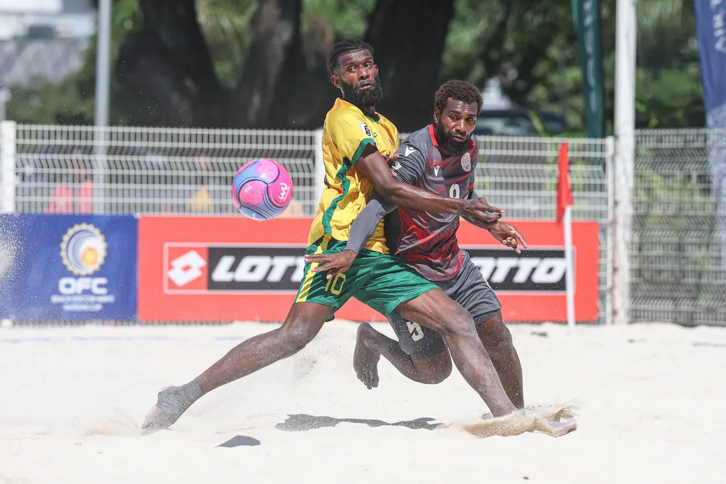 A player in yellow and green competes for the ball with an opponent in grey and red at the OFC Beach Soccer Men's Nations Cup 2026 at Aorai Tini Hau, Pirae.