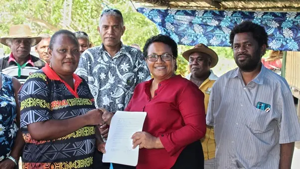 Wendy Saki Besa’a, a cassava out-grower got her signed agreement from MAL PS, Ethel Francis as Sape Farm Managing Director, Dr. Paul Bosawai Popora (right) and Undersecretary Technical Michael Ho’ota (from back row) looks on.