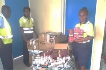Customs Officers with the seized cigarettes.
