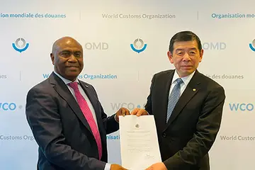 Ambassador Mose and WCO Secretary-General Dr. Kunio Mikuriya showing membership certificate.