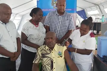 Supervising Premier Hon. Isaac Tatapu ready to receive his vaccination with which was witnessed by (back row from left) MHMS Director Planning Mr. Ivan Ghemu, Health PS Mrs Pauline McNeil and Western Provincial Health Director Dr Dickson Boara.